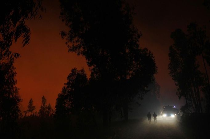 People walk on a road near a forest fire burning in Ribeira do Farrio, near Ourem September 3, 2012. According to the civil defence, over 1,700 firefighters have been mobilized to tackle more than 10 forest fires currently active in Portugal. A man died and three people were injured so far. REUTERS/Rafael Marchante (PORTUGAL - Tags: DISASTER ENVIRONMENT) Published: Zář. 4, 2012, 12:36 dop.