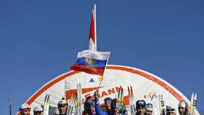 Ilja Černousov (uprostřed) ze štafety Ruska mává státní vlajkou po vítězství štafety na 4 x 10 km na SP v Davosu.