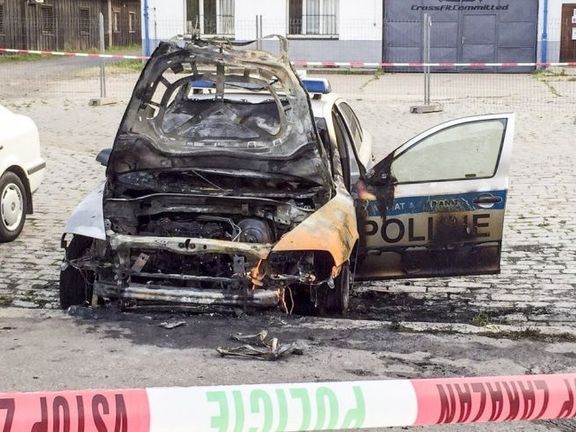 Jedno z policejních aut zapálené údajnou Sítí revolučních buněk.