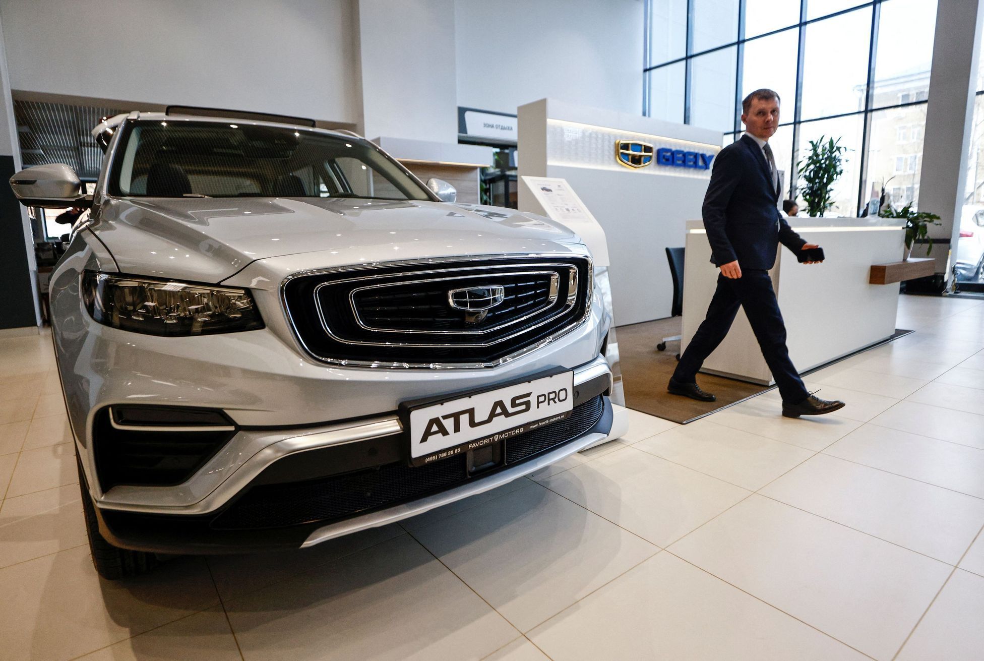 A man walks past a car produced by Chinese automobile manufacturer Geely at a dealership in Moscow
