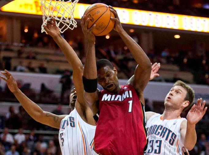 Chris Bosh se pod košem probíjí přes Dominika McGuireho a Matta Carrolla