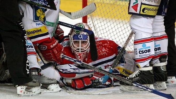 Pardubický gólman Ján Lašák ve změti těl a hokejek kryje jednu ze šancí Sparty v šestém finále extraligy.