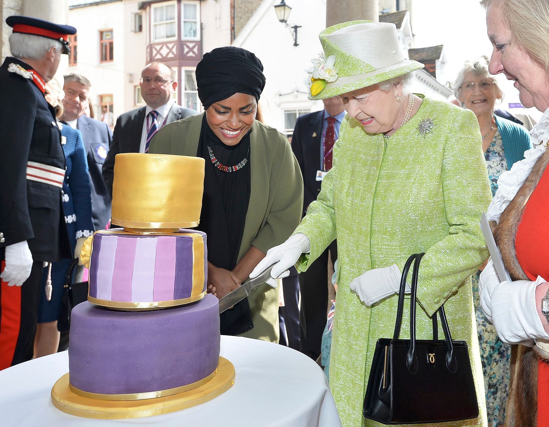 Britain's Queen Elizabeth cuts the cake Nadiya Hussain, winner of the Great British Bake Off baked for her, as she walks through Windsor on her 90th Birthday, in Windsor