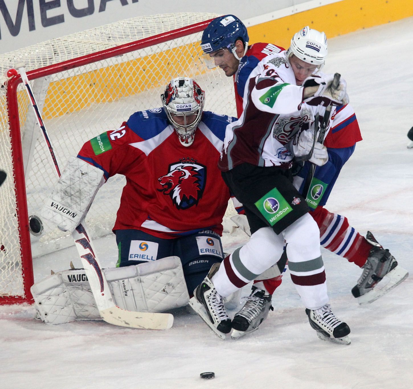 Hokejový brankář Tomáš Pöpperle chrání branku před Meijou Gintsem v utkání KHL 2012/13 mezi Lvem Praha s Dinamem Riga .