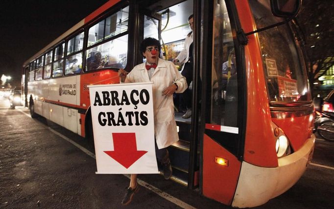 A member of the Traffic Psychologists gets off a bus as he holds a banner that reads "Free Hugs" during his performance in Sao Paulo July 23, 2012. Traffic Psychologists is a non-profit non-governmental organization which aims to humanize traffic and reduce the level of stress caused to drivers. Sao Paulo has more than 7 million vehicles, according to figures from the state transport authority Detran. Picture taken July 23, 2012. REUTERS/Nacho Doce (BRAZIL - Tags: TRANSPORT SOCIETY TPX IMAGES OF THE DAY) Published: Čec. 24, 2012, 7:02 dop.