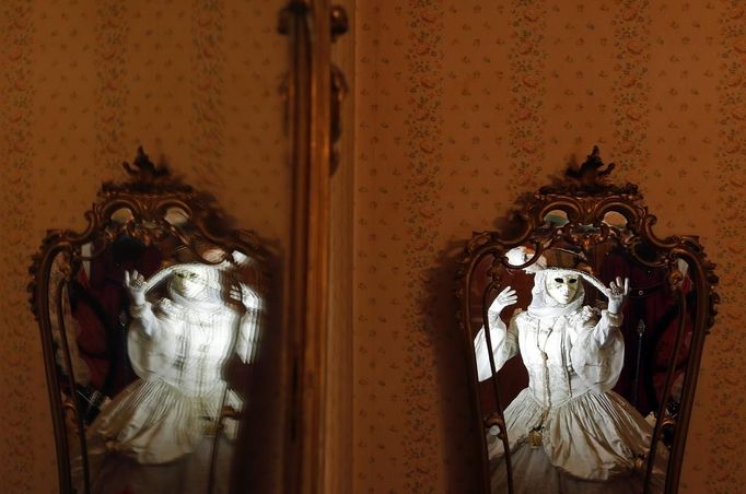 Nadia, wife of Marco Dilauro, is reflected in mirrors as she wears one of his creations, an elaborate costume for the Venice Carnival January 25, 2013. Marco Dilauro, 43, is a tax collector by day, but his real passion is making masks and costumes for the carnival. A resident of Como, northern Italy, he chooses fabrics, ribbons, lace and costume jewellery to make the period costumes after doing extensive research, and wears them at Carnival, which ends on the day before Ash Wednesday. Picture taken January 25, 2013. REUTERS/Alessandro Bianchi (ITALY - Tags: SOCIETY TPX IMAGES OF THE DAY) Published: Led. 27, 2013, 11:48 odp.