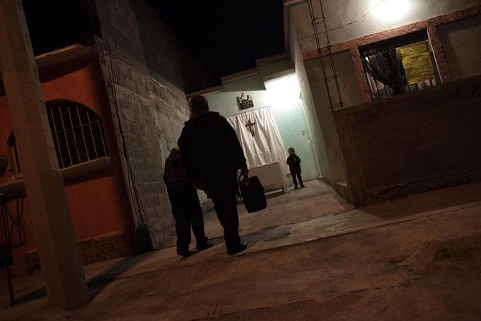 Catholic priest Adolfo Huerta, known as "Gofo", walks with a child to a place between two houses where he will conduct mass in Saltillo February 26, 2013. Ordained five years ago, Huerta is an unconventional priest who likes rock music, dyes the ends of his hair red, dresses in black, and enjoys riding his motorcycle. Huerta found God and priesthood while studying philosophy at the Pontifical University in Mexico City and working with HIV-positive patients and sex workers as a social activist. He says it is important to demystify faith and accept people's differences without judgment, and in his sermons he references rock songs, quotes books and tells jokes. Picture taken February 26, 2013. REUTERS/Daniel Becerril (MEXICO - Tags: RELIGION SOCIETY) ATTENTION EDITORS: PICTURE 8 OF 26 FOR PACKAGE 'CHURCH, FAITH AND ROCK'N ROLL' SEARCH 'PRIEST DANIEL' FOR ALL IMAGES Published: Bře. 15, 2013, 10:22 dop.