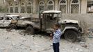 A boy holding a toy rifle stands at the site of a car bomb attack in Yemen's capital Sanaa July 21, 2015. Islamic State's Yemen branch claimed responsibility for a car