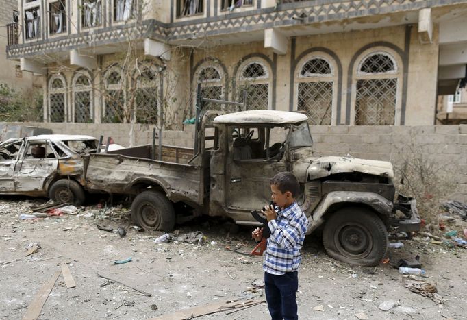 A boy holding a toy rifle stands at the site of a car bomb attack in Yemen's capital Sanaa July 21, 2015. Islamic State's Yemen branch claimed responsibility for a car