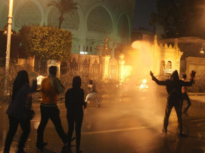 Protesters opposing Egyptian President Mohamed Mursi and the Muslim Brotherhood chant anti-government slogans and throw stones while police spray water on them from inside the Presidential Palace, as some of the protesters try to break through one of the gates of the palace, in Cairo February 11, 2013. Protesters demanding the departure of Mursi clashed with police outside his palace on Monday on the second anniversary of the overthrow of veteran autocrat Hosni Mubarak. Dozens of youths threw rocks at the Ettihadiya palace after a peaceful march by thousands of demonstrators who accused Mursi's conservative Muslim Brotherhood of hijacking Egypt's democratic revolution and seeking to monopolise power. REUTERS/Asmaa Waguih (EGYPT - Tags: POLITICS CIVIL UNREST) Published: Úno. 11, 2013, 8:56 odp.