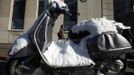 A woman walks past a snow covered Vespa in New York, February 9, 2013. A blizzard pummelled the Northeastern United States, killing at least one person, leaving hundreds of thousands without power and disrupting thousands of flights, media and officials said. REUTERS/Carlo Allegri (UNITED STATES - Tags: ENVIRONMENT) Published: Úno. 10, 2013, 12:15 dop.