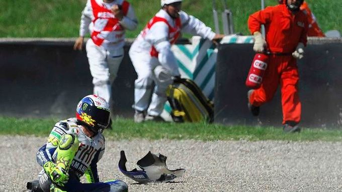 Valentino Rossi se drží po pádu za nohu. Je zle