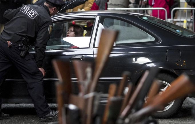 A Seattle Police Officer talks with a woman during a gun buyback event in Seattle, Washington January 26, 2013. Participants received up to a $100 gift card in exchange for working handguns, shotguns and rifles, and up to a $200 gift card for assault weapons. The event lasted from 9 a.m. until shortly after noon, after the event ran out of $80,000 worth of gift cards. REUTERS/Nick Adams (UNITED STATES - Tags: POLITICS CIVIL UNREST) Published: Led. 27, 2013, 12:46 dop.