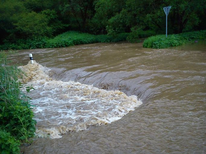 Hladina Stroupímského potoka v obci Hředle na Berounsku. Pod hladinou se nachází silnice směr Točník - Bzová.