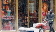 Mužu uklízí sníh z chodníku před svým obchodem v Bostonu, Massachusetts