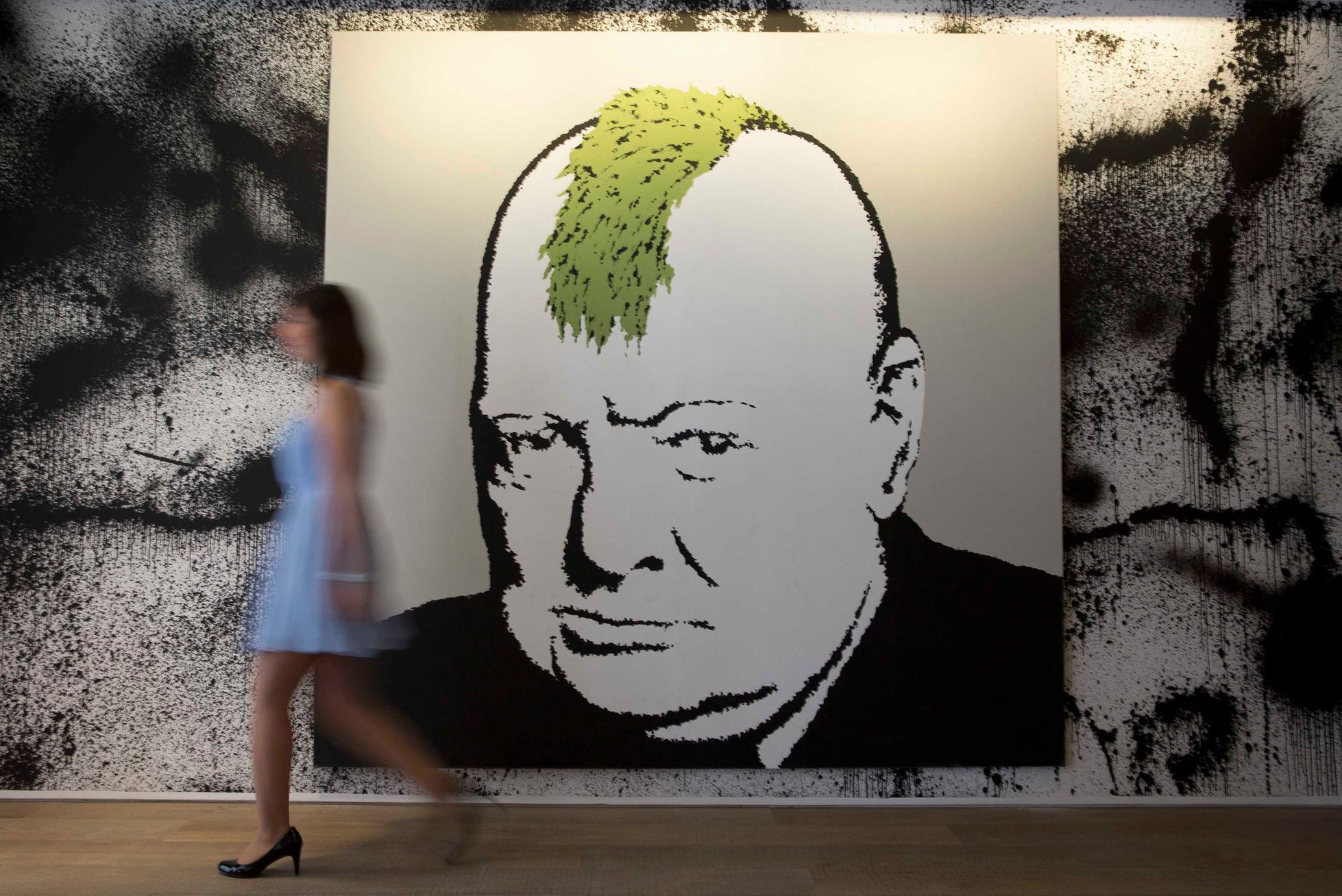 A gallery assistant walks past work depicting Churchill at Banksy: The Unauthorised Retrospective at Sotheby's S2 Gallery in London