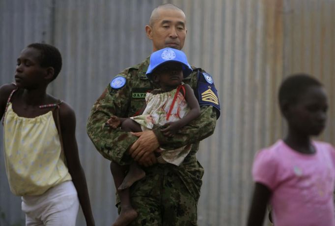 United Nations peacekeeping engineer from Japanese GSDF carries child inside CCC Centre for girls in Juba capital of South Sudan