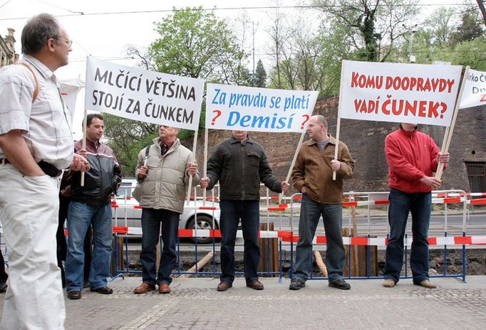 Náhodný kolemjdoucí si prohlíží transparenty, které lidé přinesli na demonstraci na podporu Jiřího Čunka před Strakovu akademii.