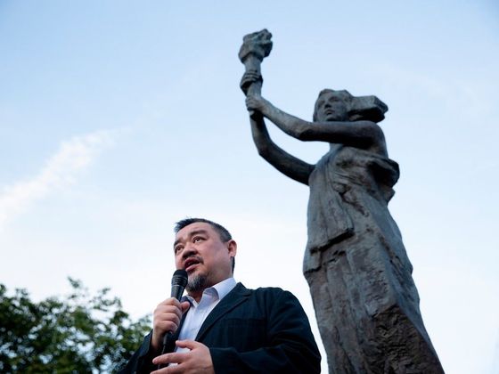 Jeden z vůdců demonstrací na náměstí Nebeského klidu (Tchien-an-men) Wu'er Kchaj-si pod kopií sochy, kterou si demonstranti v roce 1989 vytvořili. Foceno v roce 2022.