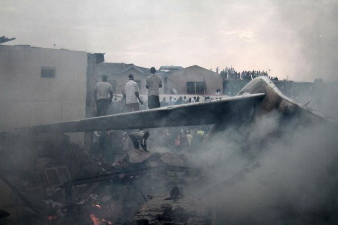 Rescue workers stand on the wing of a plane after it crashed into a neighbourhood in Ishaga disrict, an outskirt of Nigeria's commercial capital Lagos June 3, 2012. There were no survivors among the 147 people on board a domestic passenger aircraft that crashed in the Nigerian city of Lagos on Sunday, an official of the National Emergency Management Agency (NEMA), told Reuters. REUTERS/Akintunde Akinleye (NIGERIA - Tags: DISASTER TRANSPORT) Published: Čer. 3, 2012, 8:21 odp.