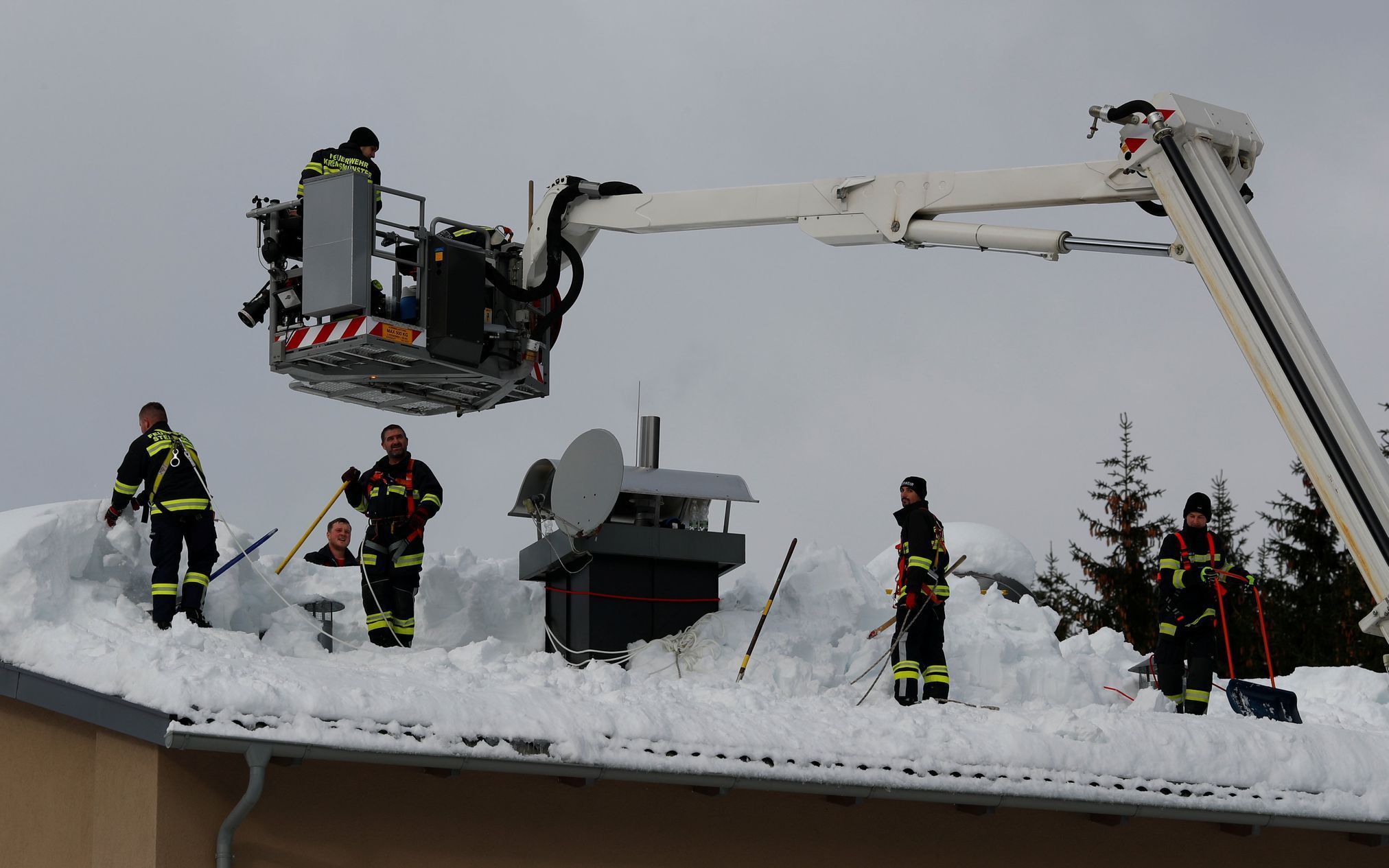 Hasiči odstraňují sníh ze střechy domu v Rosenau v Rakousku.
