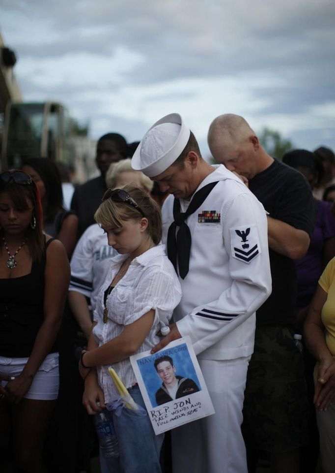 Keith Hoover (R) and Monica Matryba pray while they hold a photo of friend Jon Blunk, killed while protecting his girlfriend in the Century 16 movie theater shootings last Friday, at a prayer vigil for the victims in Aurora, Colorado July 22, 2012. Thousands of Denver-area residents made a sunset pilgrimage to a sprawling park on Sunday to honor the 12 who died and the scores more wounded when a gunman opened fire early Friday in a crowded midnight movie. REUTERS/Rick Wilking (UNITED STATES - Tags: CRIME LAW CIVIL UNREST OBITUARY) Published: Čec. 23, 2012, 4:48 dop.