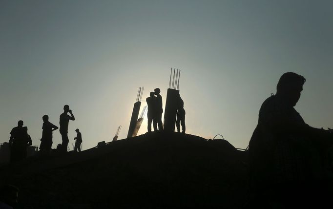 Palestinci stojí na troskách domu, který zničil izraelský letecký nálet.