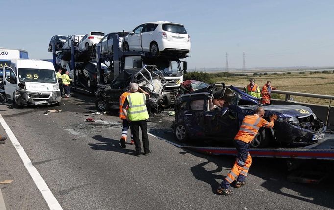 A rescue worker pushes a car on to a recovery truck amongst the wreckage of some of the 100 vehicles involved in multiple collisions, which took place in dense fog during the morning rush hour, on the Sheppey Bridge in Kent, east of London, September 5, 2013. Eight people were seriously injured and dozens hurt in the multiple crashes.