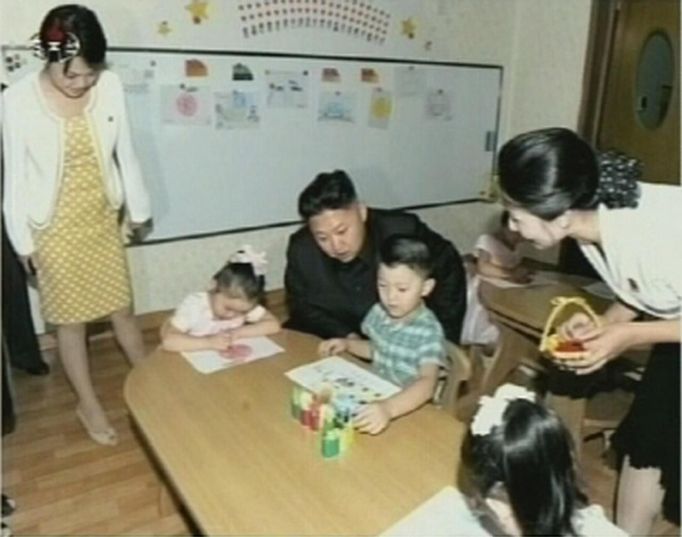 North Korean leader Kim Jong-un visits a pre-school as an unidentified woman stands near him in Pyongyang in this undated still image aired on video. REUTERS/KRT via Reuters TV (NORTH KOREA - Tags: POLITICS) FOR EDITORIAL USE ONLY. NOT FOR SALE FOR MARKETING OR ADVERTISING CAMPAIGNS. THIS IMAGE HAS BEEN SUPPLIED BY A THIRD PARTY. IT IS DISTRIBUTED, EXACTLY AS RECEIVED BY REUTERS, AS A SERVICE TO CLIENTS. NORTH KOREA OUT. NO COMMERCIAL OR EDITORIAL SALES IN NORTH KOREA Published: Čec. 15, 2012, 5:26 dop.