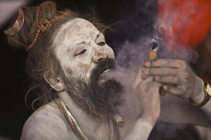 A Sadhu, or a Hindu holy man, smokes marijuana on a chillum on the banks of river Ganges ahead of the "Kumbh Mela" (Pitcher Festival) in the northern Indian city of Allahabad January 11, 2013. During the festival, Hindus take part in a religious gathering on the banks of the river Ganges. "Kumbh Mela" will return to Allahabad in 12 years. REUTERS/Ahmad Masood (INDIA - Tags: RELIGION SOCIETY) Published: Led. 11, 2013, 6:22 odp.