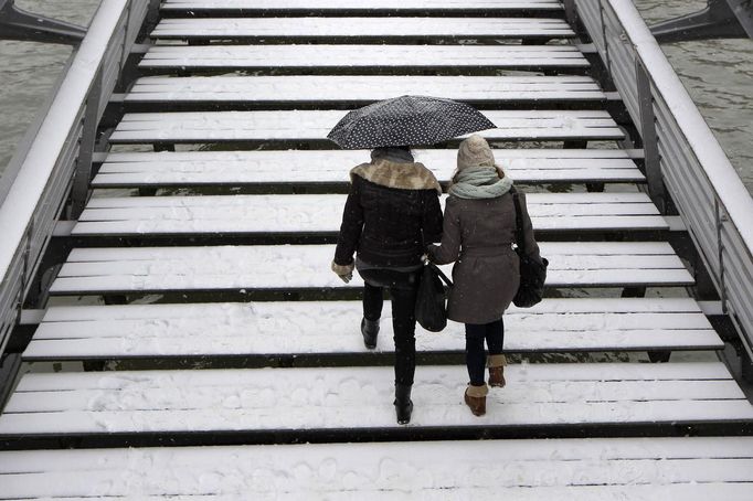 Women holding an umbrella walk on a snow-covered bridge over the River Seine in Paris March 12, 2013 as winter weather with snow and freezing temperatures returns to northern France. REUTERS/Gonzalo Fuentes (FRANCE - Tags: ENVIRONMENT) Published: Bře. 12, 2013, 3:05 odp.