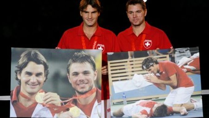 Roger Federer a Stanislas Wawrinka pózují s obrazy dokládajícími jejich olympijský triumf v Pekingu.