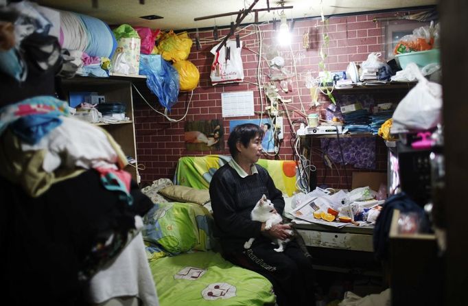 Xiao Cao, a 57-year-old gay man, watches television with his cat in his eight-square-metre apartment in Shanghai April 6, 2012. China's gay community has long been on the edges of society but it is gradually becoming more accepted. Cao, who is an unemployed drag queen, is one whose life lifts the curtain on a less romanticised view of Chinese homosexuals. Living in an eight-square-metre apartment behind a public toilet and with a monthly income of 500 yuan ($79) from social insurance, he passes his days dancing in public and spending time with friends at gay clubs. Picture taken April 6, 2012. REUTERS/Aly Song (CHINA - Tags: SOCIETY) CHINA OUT. NO COMMERCIAL OR EDITORIAL SALES IN CHINA. ATTENTION EDITORS PICTURE 02 OF 28 OF PACKAGE 'GAY AND OUT IN CHINA' TO FIND ALL IMAGES SEARCH 'GAY OUT CHINA' Published: Čer. 1, 2012, 12:33 dop.