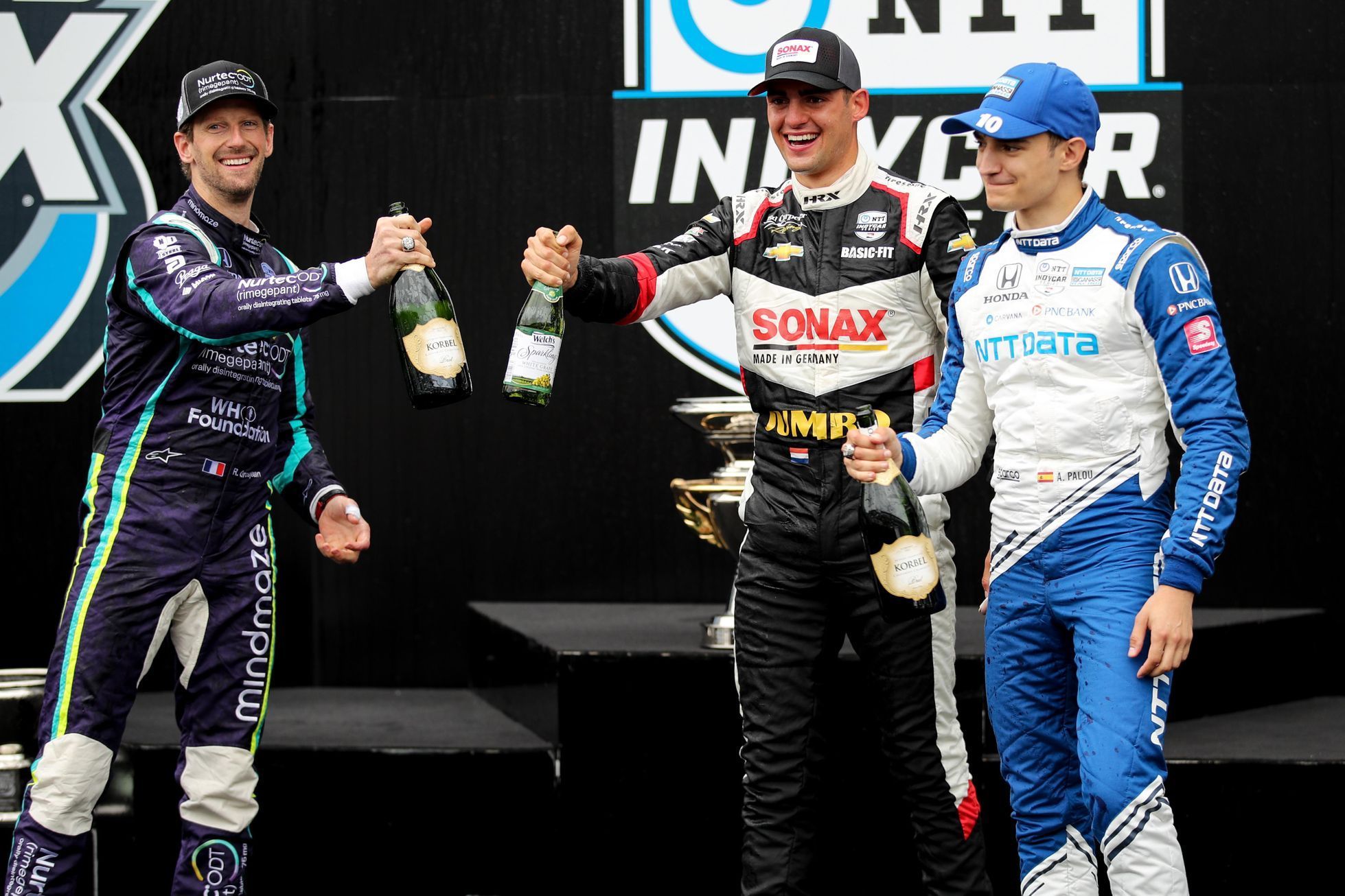 Romain Grosjean, Rinus VeeKay a Álex Palou na stupních vítězů závodu IndyCar Grand Prix of Indianapolis 2021