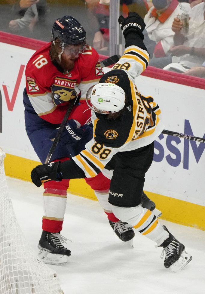 Marc Staal z Floridy (18) posílá k zemi útočníka Bostonu Davida Pastrňáka.