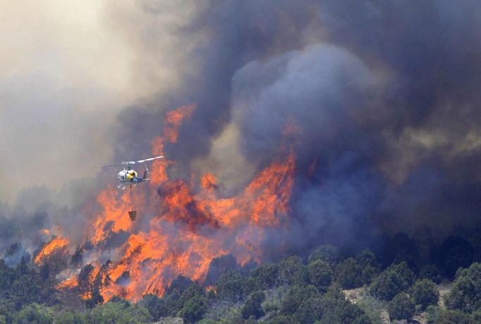 A fire fighting helicopter drops water over the Wood Hollow fire, north of Fairview, Utah, June 26, 2012. More than 500 structures have been threatened by the Wood Hollow fire, forcing up to 1,500 people from homes. REUTERS/George Frey (UNITED STATES - Tags: ENVIRONMENT DISASTER) Published: Čer. 26, 2012, 9:31 odp.