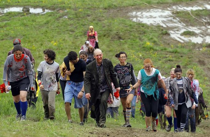 Zombies walk off the course after chasing runners on the "Run for Your Lives" 5K obstacle course race in Amesbury, Massachusetts May 5, 2012. Runners face man-made and natural obstacles on the course, while being chased by zombies, who try to take "health" flags off the runners belts. REUTERS/Brian Snyder (UNITED STATES - Tags: SOCIETY TPX IMAGES OF THE DAY) Published: Kvě. 5, 2012, 10:28 odp.