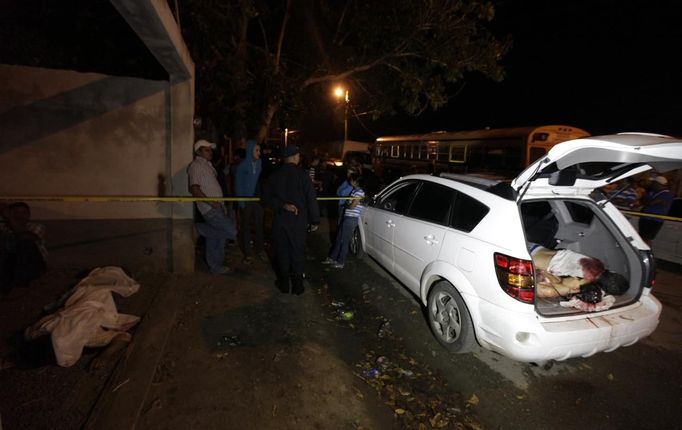 ATTENTION EDITORS - VISUALS COVERAGE OF SCENES OF DEATH AND INJURY A police officer talks to bystanders at a crime scene near the bodies of the victims in the city of San Pedro Sula March 22, 2013. Unknown assailants killed three men and one woman on Friday at the crime scene in a working class neighbourhood, local media reported. San Pedro Sula has been labelled the most violent city on the planet, according to a U.N. Development Program report last week. Picture taken March 22, 2013. REUTERS/Jorge Cabrera (HONDURAS - Tags: CIVIL UNREST CRIME LAW) TEMPLATE OUT Published: Bře. 23, 2013, 9:01 odp.