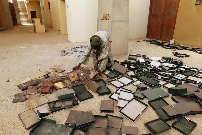 A museum guard picks up boxes holding ancient manuscripts, which were partially damaged by Islamist rebels, at the Ahmed Baba Institute, or Ahmed Baba Centre for Documentation and Research, in Timbuktu January 31, 2013. The majority of Timbuktu's ancient manuscripts appear to be safe and undamaged after the Saharan city's 10-month occupation by Islamist rebel fighters, experts said on Wednesday, rejecting some media reports of their widespread destruction. REUTERS/Benoit Tessier (MALI - Tags: POLITICS CIVIL UNREST CONFLICT SOCIETY) Published: Led. 31, 2013, 8:04 odp.