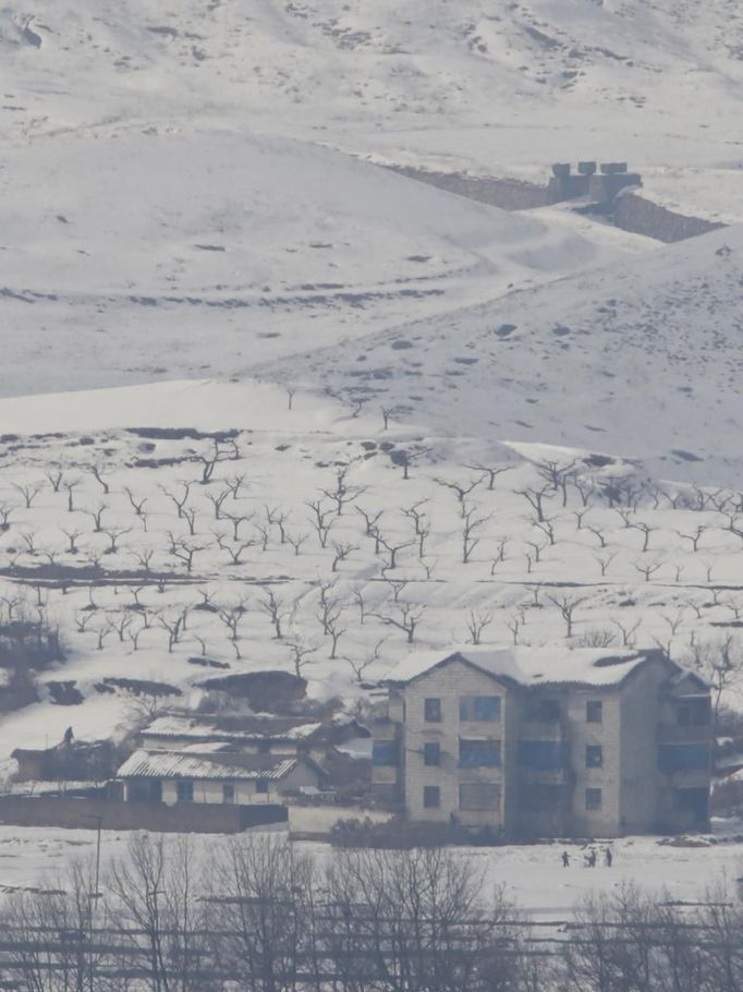 North Korean children (bottom R) make a snowman in the village of Gijungdong, North Korea, in this picture taken from a South Korean observation post, just south of the demilitarized zone separating the two Koreas, in Paju, north of Seoul, February 6, 2013. New York under missile attack is a remote dream for impoverished North Korea, yet that is precisely what the latest propaganda video from the isolated state shows as it readies a third nuclear test. North Korea has trailed plans to carry out a third nuclear test, which experts believe is imminent. REUTERS/Lee Jae-Won (SOUTH KOREA - Tags: MILITARY POLITICS ENERGY CONFLICT SOCIETY) Published: Úno. 6, 2013, 8:07 dop.