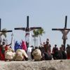 Ruben Enaje (C), 52, who is portraying Jesus Christ for the 27th time, hangs on a cross beside two men, who portray Dismas and Gestas, after he was nailed to it during a Good Friday crucifixion re-enactment in San Pedro Cutud town, Pampanga province, north of Manila March 29, 2013. The Roman Catholic church frowns on the gory spectacle held in the Philippine village of Cutud every Good Friday but does nothing to deter the faithful from emulating the suffering of Christ and taking a painful route to penitence. Holy Week is celebrated in many Christian traditions during the week before Easter. REUTERS/Romeo Ranoco (PHILIPPINES - Tags: RELIGION SOCIETY) Published: Bře. 29, 2013, 7:54 dop.