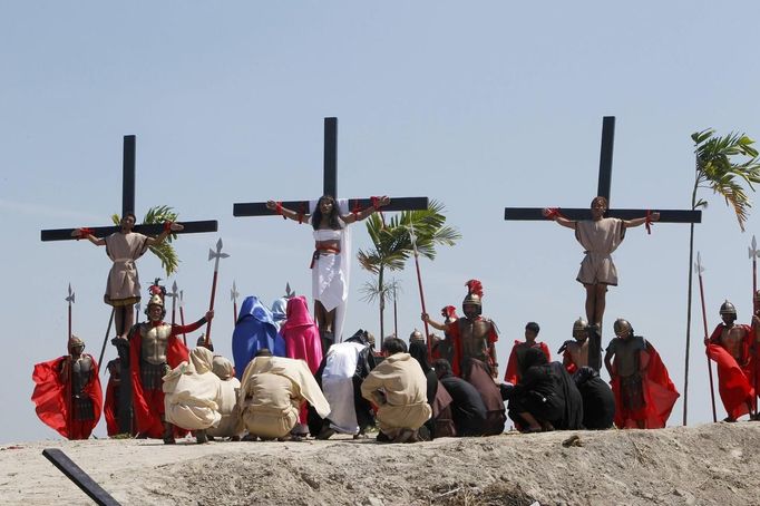 Ruben Enaje (C), 52, who is portraying Jesus Christ for the 27th time, hangs on a cross beside two men, who portray Dismas and Gestas, after he was nailed to it during a Good Friday crucifixion re-enactment in San Pedro Cutud town, Pampanga province, north of Manila March 29, 2013. The Roman Catholic church frowns on the gory spectacle held in the Philippine village of Cutud every Good Friday but does nothing to deter the faithful from emulating the suffering of Christ and taking a painful route to penitence. Holy Week is celebrated in many Christian traditions during the week before Easter. REUTERS/Romeo Ranoco (PHILIPPINES - Tags: RELIGION SOCIETY) Published: Bře. 29, 2013, 7:54 dop.