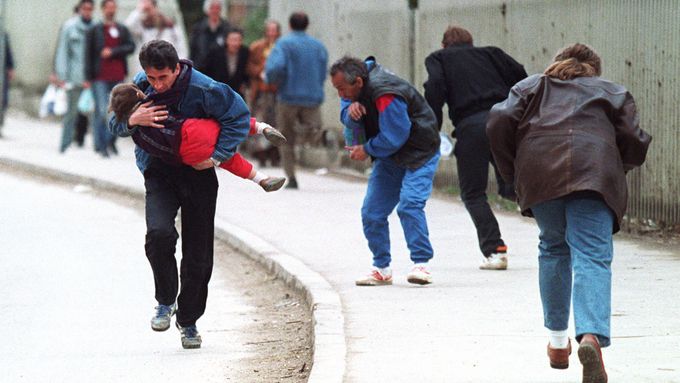 Bosenský muž s dítětem v náručí s ostatními chodci utíká před ostřelovačem, Sarajevo, duben 1993.
