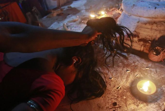 A man holds a devotee who is believed to be possessed by evil spirits by her hair while confronting her as she goes into a state of trance while lying on a sacred platform at Guru Deoji Maharaj temple during a ghost fair at Malajpur village in Betul district in the central Indian state of Madhya Pradesh January 26, 2013. People from across India come to this fair to be exorcised of �evil spirits�. They are usually brought by relatives and they are most often women. The exorcism involves running around the temple courtyard to make the 'ghost' weak then being beaten by a priest with a broom. Picture taken January 26, 2013. REUTERS/Danish Siddiqui (INDIA - Tags: SOCIETY RELIGION) ATTENTION EDITORS: PICTURE 21 OF 24 FOR PACKAGE 'INDIAN GHOSTBUSTERS' SEARCH 'INDIA GHOST' FOR ALL IMAGES Published: Úno. 5, 2013, 5:10 dop.