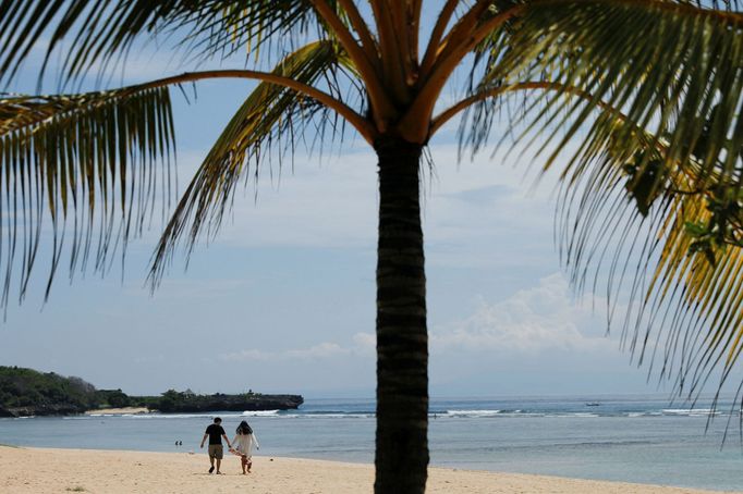 Pár se prochází na pláži Nusa Dua na Bali.