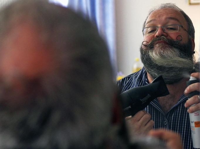 German hairdresser Elmar Weisser, 48, is reflected in a mirror in his hotel room as he starts shaping his beard as a stork to compete in the 2012 European Beard and Moustache Championships in Wittersdorf near Mulhouse, Eastern France, September 22, 2012. Weisser, who won the World Beard and Moustache Championship in 2011, ranked second in the freestyle category of the European championships on Saturday. Picture taken September 22, 2012. REUTERS/Vincent Kessler (FRANCE - Tags: SOCIETY) Published: Zář. 23, 2012, 11:54 dop.