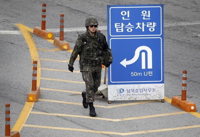 A South Korean soldier patrols as South Korean trucks leave the South's CIQ (Customs, Immigration and Quarantine) office to go to the inter-Korean Kaesong Industrial Complex in North Korea, just south of the demilitarised zone separating the two Koreas, in Paju, north of Seoul, April 1, 2013. North Korea said on Saturday it was entering a "state of war" with South Korea, but Seoul and the United States played down the statement as tough talk. Pyongyang also threatened to close a border industrial zone, the last remaining example of inter-Korean cooperation which gives the North access to $2 billion in trade a year. The sign reads, "Vehicle carrying passengers (top). 50m U-turn." REUTERS/Lee Jae-Won (SOUTH KOREA - Tags: MILITARY POLITICS BUSINESS) Published: Dub. 1, 2013, 3:04 dop.