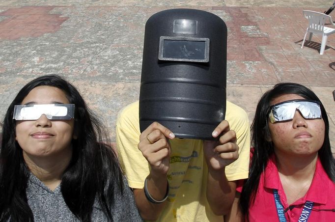 Students use a welding mask (C) and eclipse glasses (L and R) to watch Venus passing between the Sun and the Earth in Luneta park in Manila June 6, 2012. Venus made a slow transit across the face of the sun on Tuesday, the last such passing that will be visible from Earth for 105 years. REUTERS/Romeo Ranoco (PHILIPPINES - Tags: POLITICS SOCIETY) Published: Čer. 6, 2012, 7:39 dop.