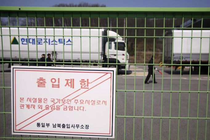 A South Korean security guard and truck drivers walk past trucks turning back to South Korea's CIQ (Customs, Immigration and Quarantine) after they were banned from entering the Kaesong industrial complex in North Korea, just south of the demilitarised zone separating the two Koreas, in Paju, north of Seoul, April 3, 2013. North Korean authorities were not allowing any South Korean workers into a joint industrial park on Wednesday, South Korea's Unification Ministry and a Reuters witness said, adding to tensions between the two countries. The sign reads "limited access authorization". REUTERS/Kim Hong-Ji (SOUTH KOREA - Tags: MILITARY POLITICS TRANSPORT BUSINESS) Published: Dub. 3, 2013, 4:40 dop.