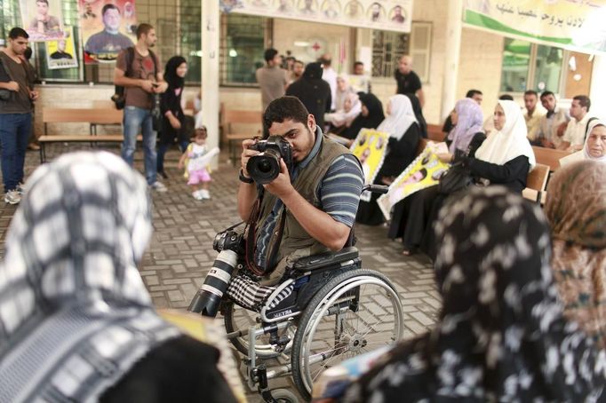 Wheelchair-bound Palestinian freelance photographer Moamen Qreiqea takes pictures of protesters calling for the release of Palestinian prisoners from Israeli jails, in Gaza City October 1, 2012. Qreiqea, 25, lost both his legs in an Israeli air strike in 2008 while taking pictures east of Gaza. The father of two is determined to continue his career despite his disability. REUTERS/Suhaib Salem (GAZA - Tags: MEDIA SOCIETY) Published: Říj. 1, 2012, 3:39 odp.